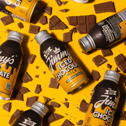The Big Jimmy's' iced chocolate milk surrounded by chocolate pieces on a yellow background