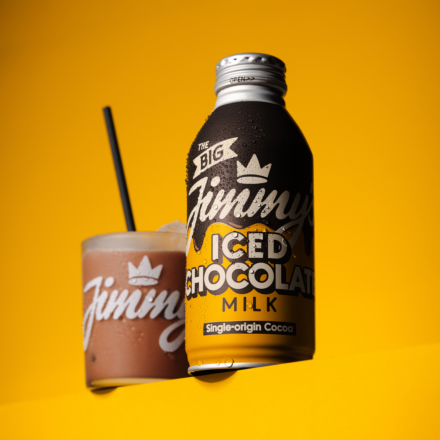 Bottle and glass of Jimmy's Iced Chocolate Milk on a yellow background