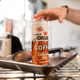 Jimmy's Iced Coffee Limited Edition Cinnamon Roll Iced Coffee Can on a bakery tray