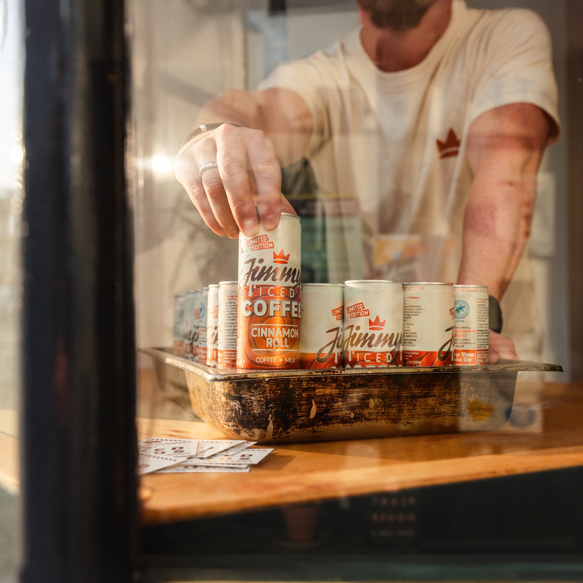 Jimmy's Iced Coffee Limited Edition Cinnamon Roll Iced Coffee Cans through a shop window