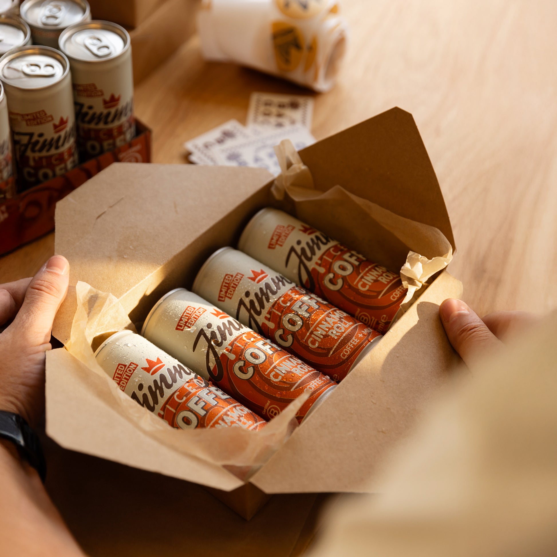 Jimmy's Iced Coffee Limited Edition Cinnamon Roll Iced Coffee Cans in a bakery delivery box